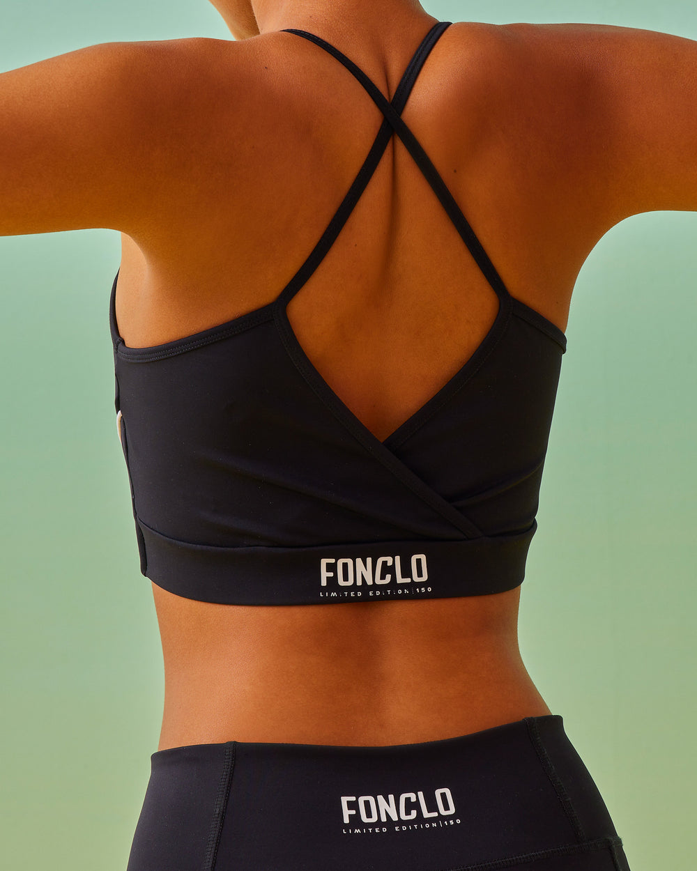 Black criss-cross strap sports bra, V-neckline, crossed straps at the back, fonclo logo on the back, high-quality, super-soft material, crop, strappy, slim fit.