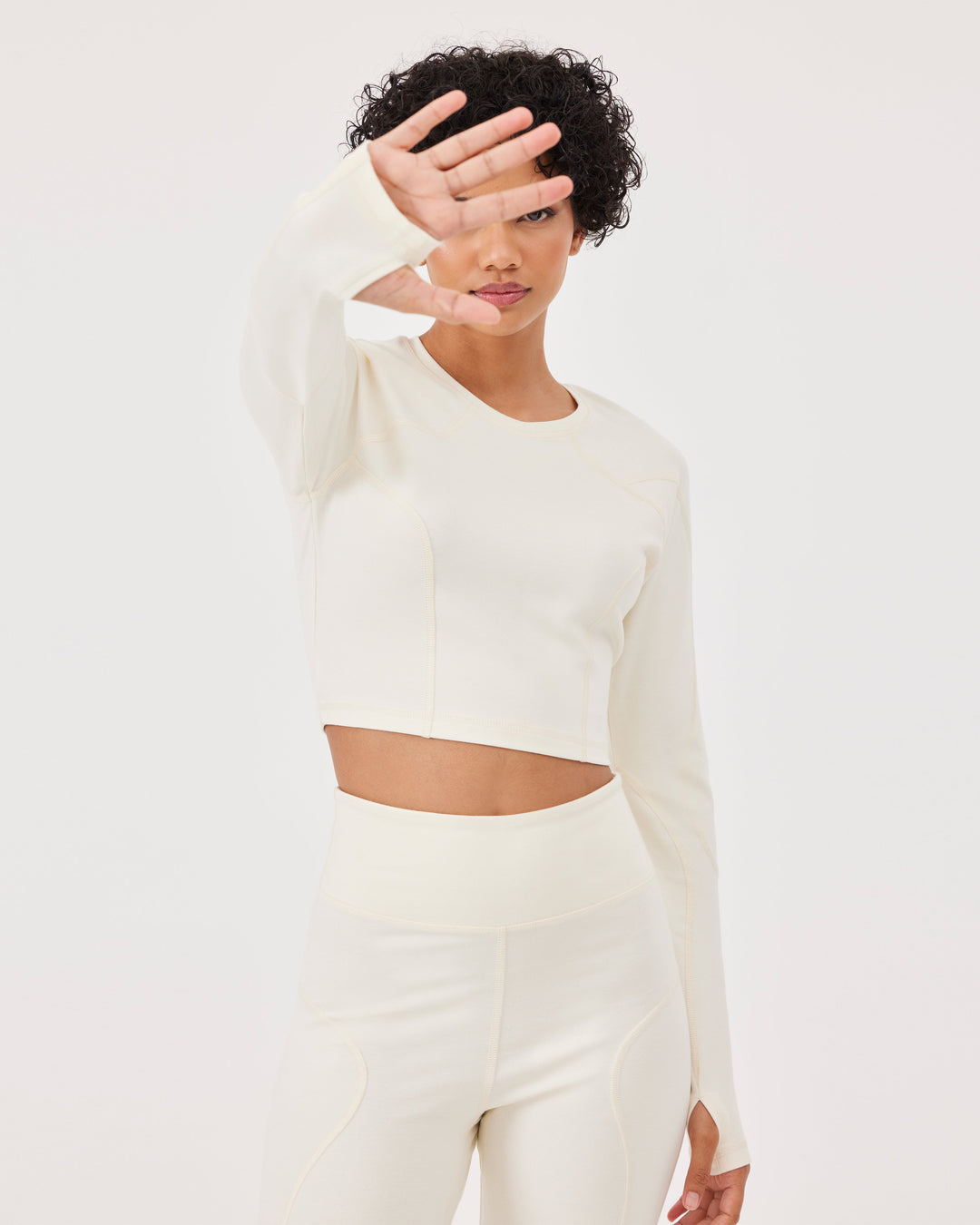 Beige long sleeved crop top, raglan sleeves, thumb holes, round neck, slim fit, high-quality stretch fabric. 