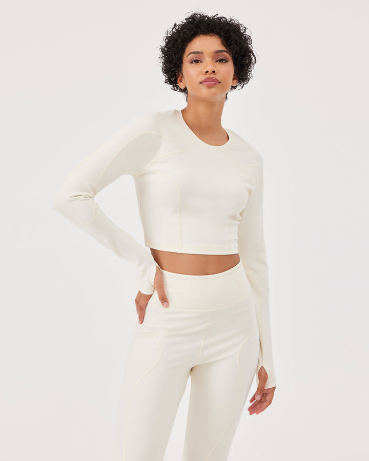 Beige long sleeved crop top, raglan sleeves, thumb holes, round neck, slim fit, high-quality stretch fabric. 