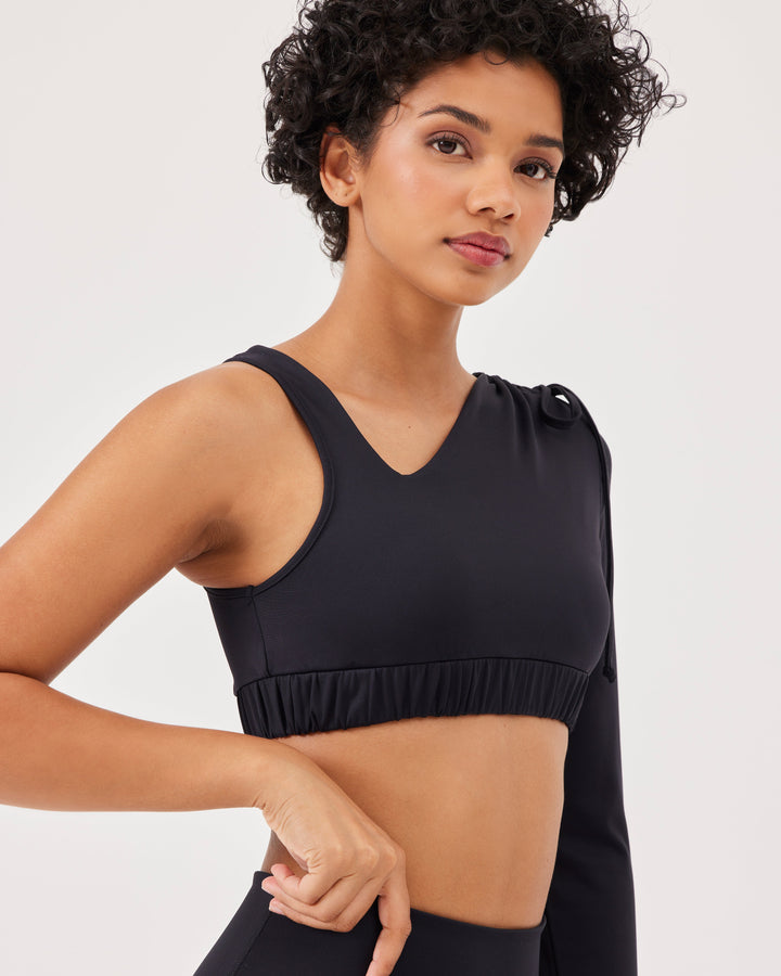 Black asymmetrical cropped top, asymmetrical sleeves, lacing on the shoulder, elastic waistband, slim fit, one long sleeve, thumb hole, sports bra. 