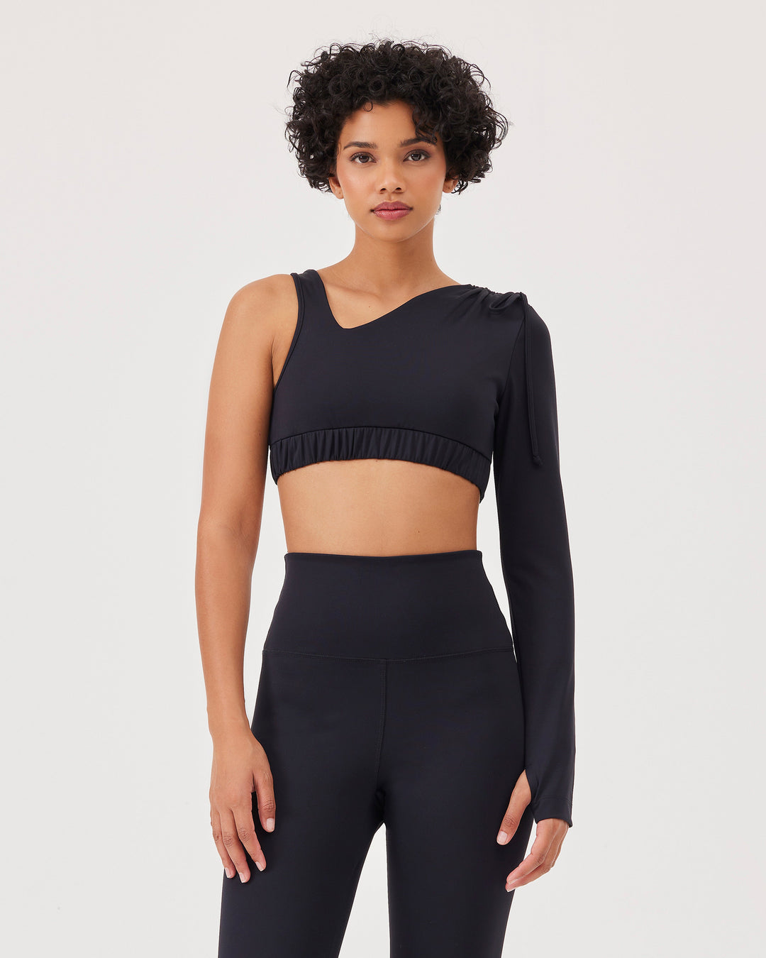 Black asymmetrical cropped top, asymmetrical sleeves, lacing on the shoulder, elastic waistband, slim fit, one long sleeve, thumb hole, sports bra. 