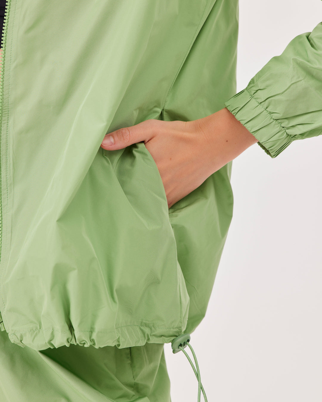 green, lightweight running jacket, front zipper, elastic drawstring at the hem,  parachute, regular fit, sport jacket, long sleeve. 