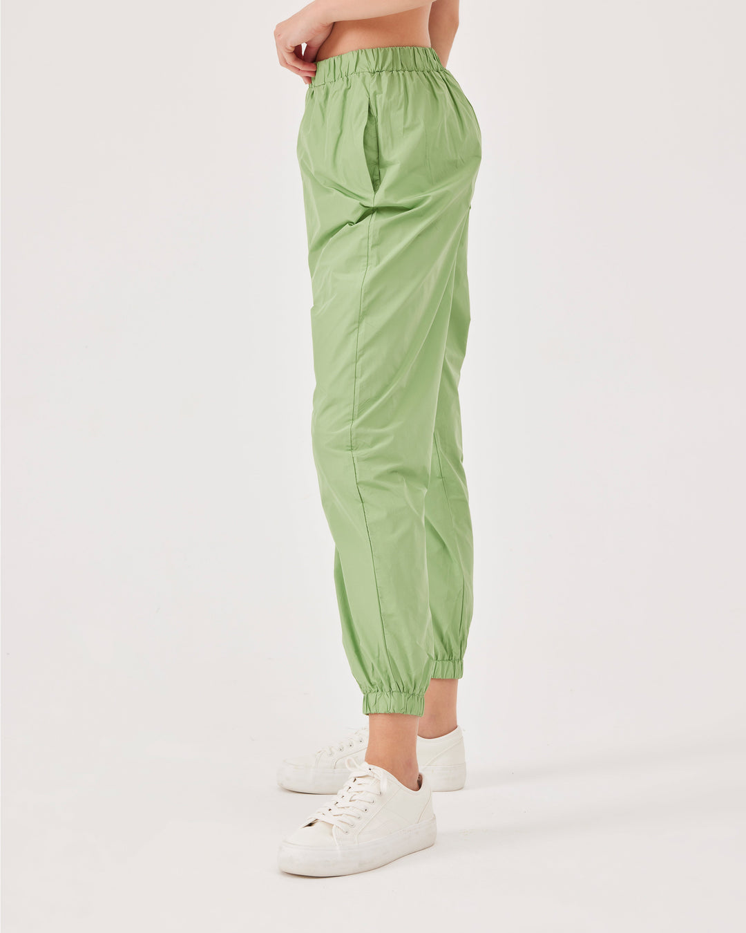 Green, lightweight running joggers, pants, elastic waistband, parachute fabric, ankle-length, regular fit, side pockets.